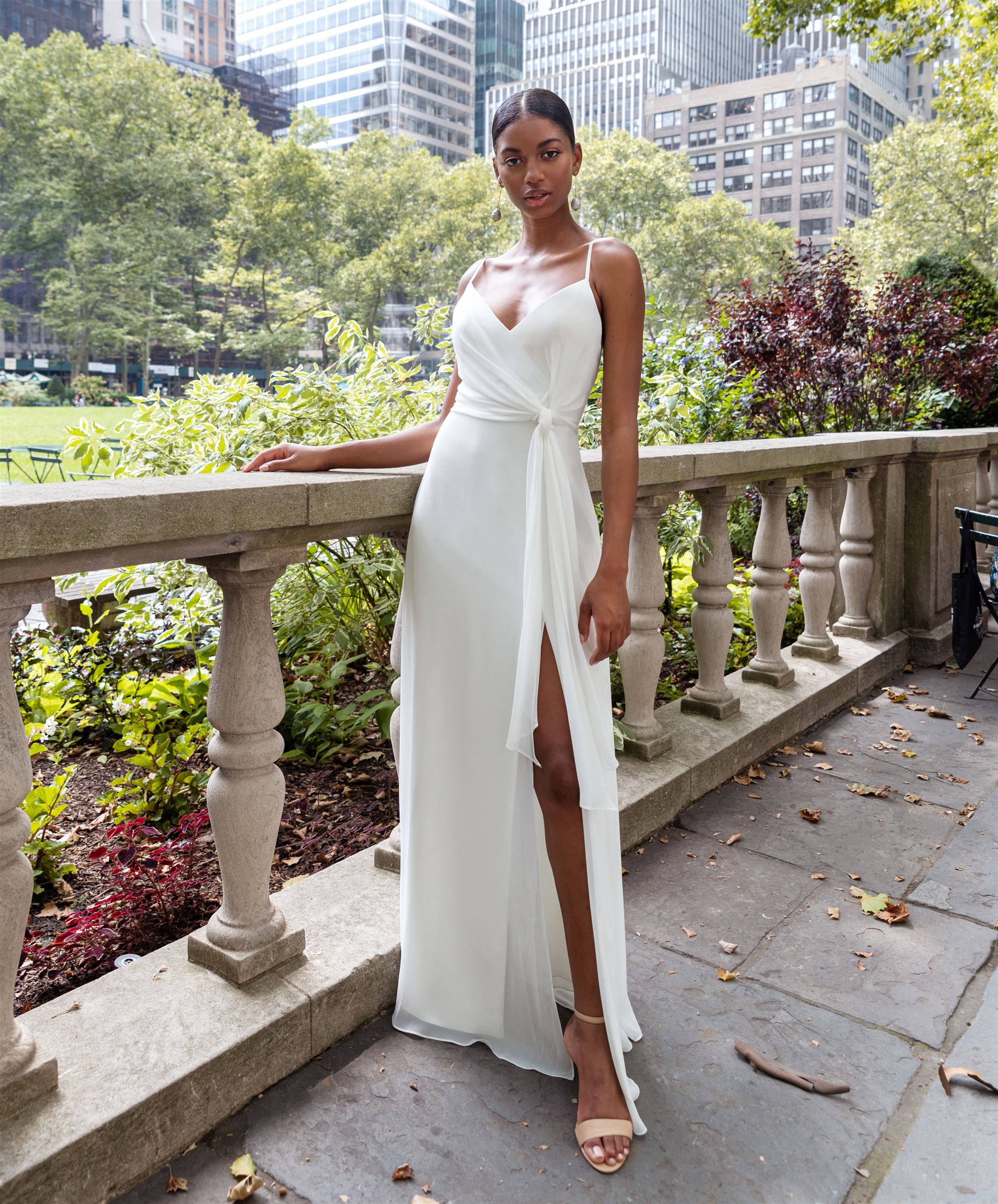 Model wearing long white dress with thigh high slit